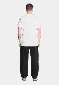 Biała bawełniana koszulka, krótki rękaw, okrągły dekolt. W zestawie z luźnymi czarnymi dżinsami. Do tego niebieskie trampki.