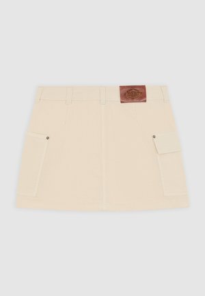 Beige kanva mini-hame, jossa on muotoiltu vyötärö, kaksi sivutaskua ja ruskea nahkalappu takana. Hameessa on suora muotoilu ja kestävä rakenne.