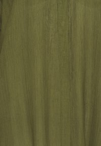 Tissu vert olive avec une texture côtelée subtile verticale et une couture centrale avec des surpiqûres visibles.
