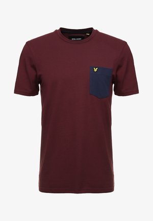 T-shirt en coton bordeaux à manches courtes, col rond, avec une poche poitrine bleu marine ornée d'un logo aigle jaune. Texture lisse, design décontracté.