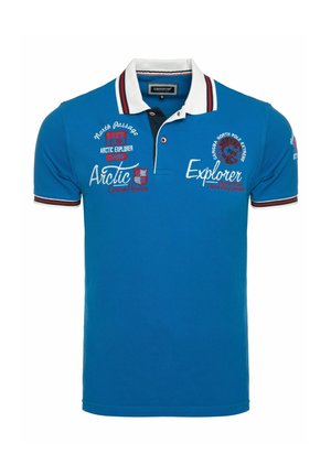 Sinine polosärk valge krae, punase ja musta triibulise äärisega, millel on tekstid Arctic Explorer ja North Pole Extreme ning tikitud plaastritega.