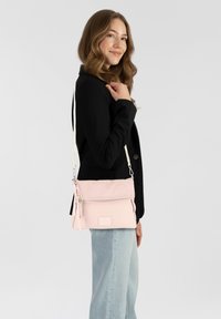 Borsa a tracolla rosa chiaro realizzata in tessuto, con una tasca con zip, dettaglio della tracolla intrecciata e cinturino regolabile.