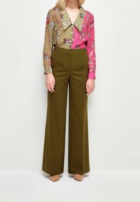 Chemise à motifs floraux avec un grand col, panneaux verts et roses ; associée à un pantalon large taille haute en olive et des escarpins nude.