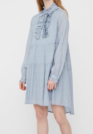 Hellblaues langärmliges Kleid mit gerafftem Kragen und plissiertem Design. Aus weichem Stoff gefertigt und mit entspanntem Schnitt, wobei der Rücken leicht länger ist.