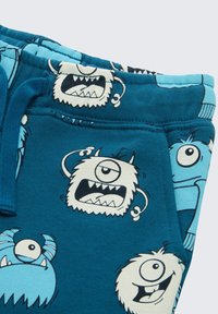 Blauwe sweatpants met een monsterpatroon in zwart en wit, gemaakt van zachte stof, met een elastische tailleband en trekkoord.