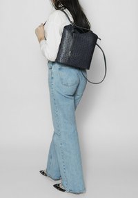 Zaino in pelle blu navy con motivo in rilievo e zip argentata, dotato di spallacci regolabili e silhouette morbida.
