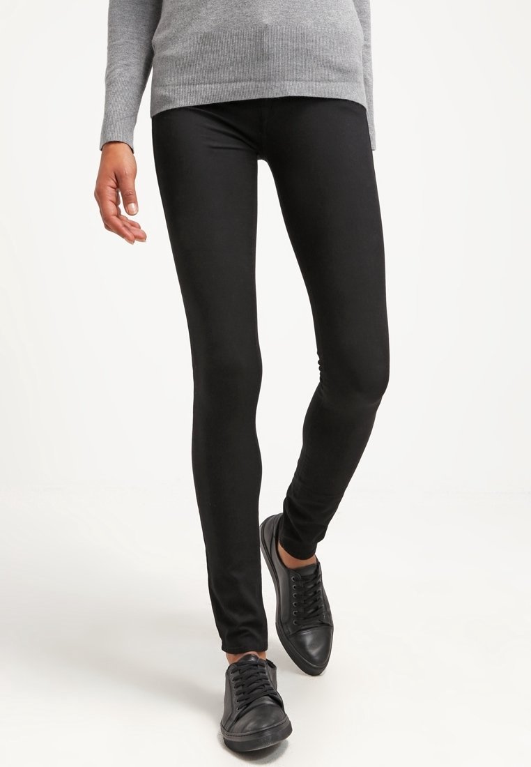Leggings negros con una textura suave, diseño ajustado y cintura elástica, combinados con zapatillas negras con cordones y una camiseta de manga larga gris.