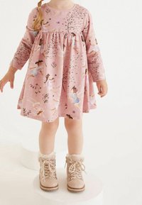 Rosa långärmad klänning med blommiga och fétrymder, samlad midja och en utsvängd kjol. Matchad med beige snörstövlar med pälsdetaljer.