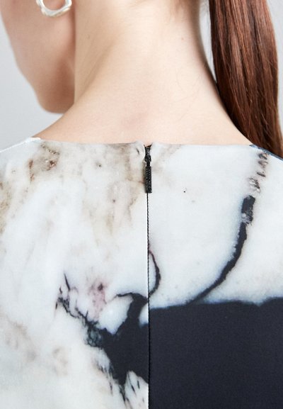 Close-up of a dress back featuring a black zipper, with an abstract marble pattern in shades of white, gray, and black. Smooth fabric texture.