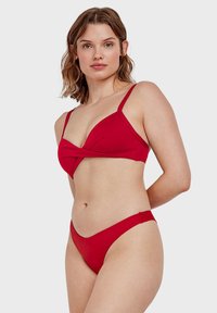 Completo bikini rosso con design anteriore arricciato sulla parte superiore, spalline sottili regolabili e slip a vita bassa. Tessuto morbido e elasticizzato.