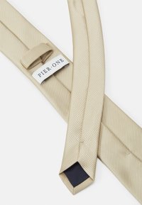 Cravate en soie beige avec des rayures diagonales, dotée d'une extrémité pointue et d'une étiquette de logo portant la mention "PIER ONE". Texture lisse et finition polie.