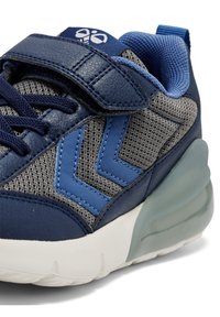 Baskets en maille bleue et en cuir avec des accents gris, dotées d'une sangle Velcro, de détails à motifs et d'une semelle épaisse et translucide.