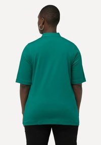 Camisa verde de manga corta con corte recto y sutiles acentos texturizados en el escote. Tela suave con un ajuste holgado.