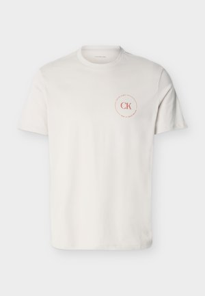 White short-sleeve crew neck T-shirt with small red circular "CK Calvin Klein" logo on left chest.