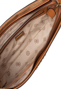 Intérieur d'un sac à main en cuir marron avec une doublure beige, présentant un motif subtil de logos. Comprend des compartiments zippés et une texture lisse.