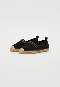 Espadrilles noires en toile avec une semelle en jute, bout rond et des détails logo discrets sur le dessus. Design à enfiler avec des côtés élastiques.