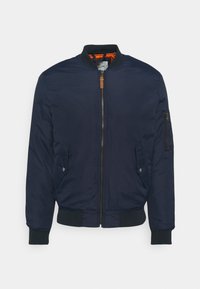 Giacca bomber blu navy con zip frontale, tasche laterali, polsini a costine e foderatura a fantasia contrastante. Realizzata in tessuto resistente.