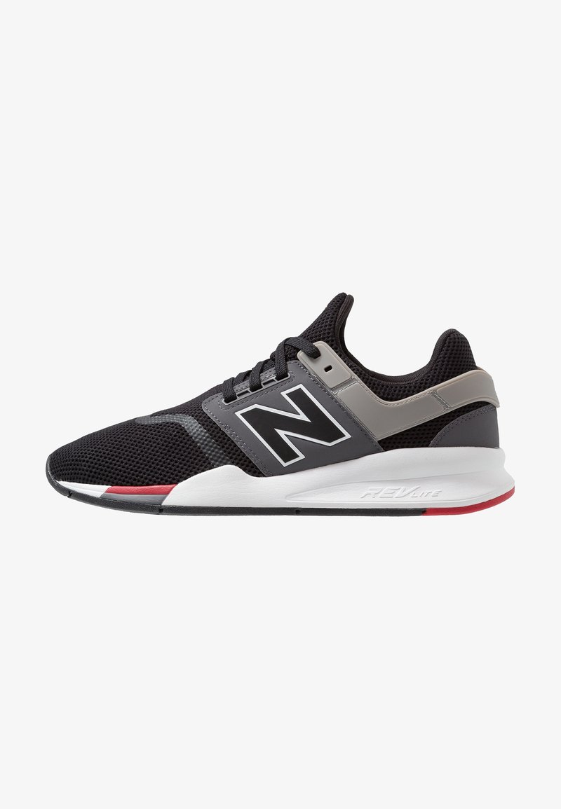 Baskets de sport noires et grises avec une tige en maille, semelle intermédiaire blanche, accents rouges et grand logo "N" sur le côté, conçues pour la course ou un usage décontracté.