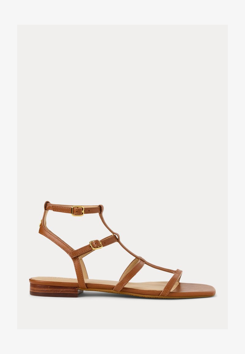 Sandal de couro castanho com várias tiras, detalhes em metal dourado e sola plana. Apresenta um design minimalista e bico aberto.