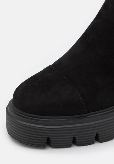Botine negre din suede cu vârful rotund, talpă groasă cu textură incrustată și design fără cusături. Prezintă o textură mată și o construcție robustă.