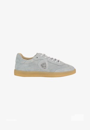 Scarpa da ginnastica in suede grigio chiaro con suola beige, design con lacci e un emblema a logo triangolare cucito sul lato.