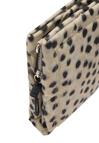 Złożona beżowa kopertówka z czarnymi plamami w leopardzi wzór, z srebrnym zamkiem błyskawicznym i czarną linką do pociągania.