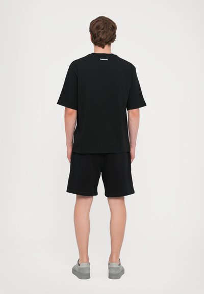 T-shirt en coton noir et short à coupe décontractée. Les caractéristiques notables incluent des manches courtes, un col rond et des accents de piqûre légers.