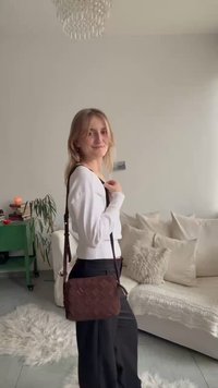 Pruun kootud õlakott tekstureeritud nahast, millel on pikk rihm ja kompaktsesse ristkülikukujulisse vormi.