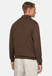 Brown knit sweater with a collared design, ribbed cuffs, and a relaxed fit. Visible texture and a brand tag near the bottom hem.