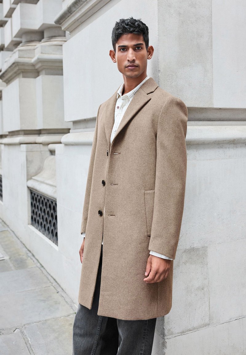 Light brown wool coat with a tailored silhouette, single-breasted design, notched lapels, and side pockets. Button closures and subtle stitching details.