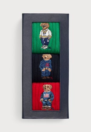 Paquete de tres calcetines de punto en verde, navy y rojo, cada uno con un oso bordado con diferentes estilos de ropa.