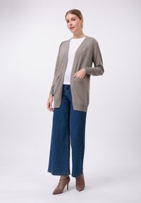 Light gray open-front cardigan made from soft fabric, featuring two front pockets. Paired with wide-leg denim jeans and brown heels.