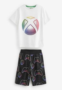 T-shirt bianca in cotone con logo Xbox colorato. Pantaloni corti neri con motivi di controller da gioco multicolori e testi in evidenza.