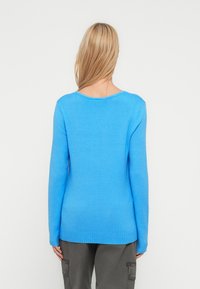 Φωτεινό μπλε πλεκτό πουλόβερ με μακριά μανίκια και στρογγυλή λαιμόκοψη. Διαθέτει ριμπ τελείωμα και λεία υφή.