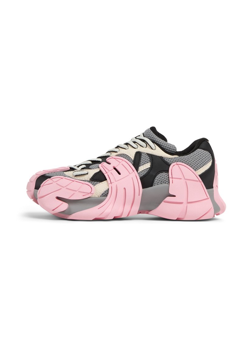 Multicolored sneaker featuring a mesh upper in gray and beige with black accents, a chunky pink sole, and a distinctive tactile design.