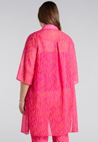 Kimono rosa trasparente con un motivo di foglie in un rosa più scuro. Il design include un colletto e maniche larghe, con orlo dritto.
