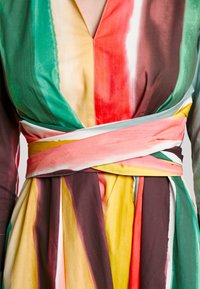 Robe colorée à rayures verticales vertes, rouges, marron, jaunes et roses. Design portefeuille avec une large ceinture assortie à la taille.