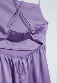 Robe en satin lavande avec fines bretelles, buste froncé avec détails en anneau, et jupe plissée, présentée sur fond blanc.