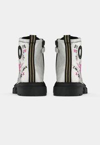 Stivaletti bianchi alla caviglia con suole nere, cerniera nera e linguetta con strisce gialle, decorati con disegni in stile graffiti rosa e neri.