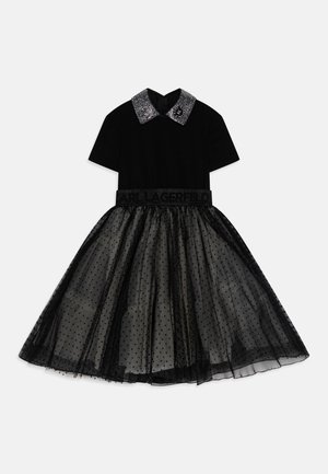 Zwarte jurk met een top met korte mouwen en een tulen rok met zwarte polka dots. Glitterkraag en tailleband met de tekst "LAGERFELD".