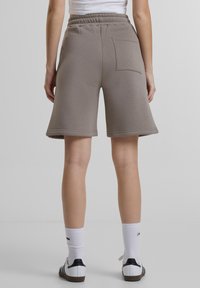 Grå bomullsshorts med sidelommer, elastisk linning og vid benkutt, med synlig sømdetalj på kanten.
