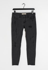 Jeans skinny de denim negro con detalles desgastados, presentan un estilo de cinco bolsillos, una cintura recta y dobladillos sin terminar para un look moderno.