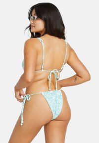 Lyseblå bikini med blomstermønster, justerbare knyter og tynne stropper. Designet inkluderer en trekantet topp og middels dekning av bunnen.