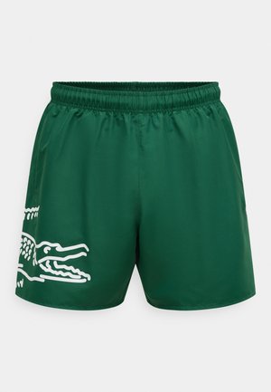 Rohelised ujumispüksid, mis on valmistatud siledast ja kergest materjalist, on küljele trükitud valge krokodillimotiiviga ning varustatud elastse vööosaga.