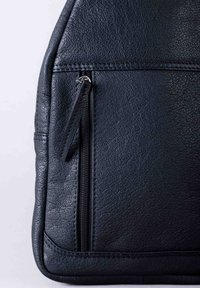 Black leather bag featuring a textured surface, angled shape, and a zippered pocket with a textured zipper pull. Stitched detailing along edges.