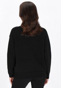 Schwarzer Pullover mit lässiger Passform, geripptem Saum und langen Ärmeln. Hergestellt aus strukturiertem Strickstoff, verfügt er über einen Rundhalsausschnitt.