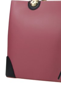 Roze, matte leren handtas met een zwart accent aan de basis, voorzien van een gouden sluiting en afgeronde bovenrand voor sluiting.