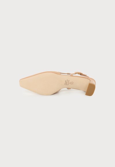 Chaussure beige à talon haut avec bout pointu et bride à la cheville, vue de la semelle, avec un petit talon bloc et une boucle.
