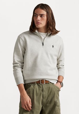 Light grey zip-up sweatshirt with ribbed cuffs, paired with olive cargo pants and a brown belt. Features a small embroidered logo on chest.