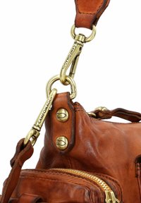 Bruine leren handtas met goudkleurige hardware, ritsdetails en een afneembare schouderband. Opvallende stiksels en klinknagelaccenten.